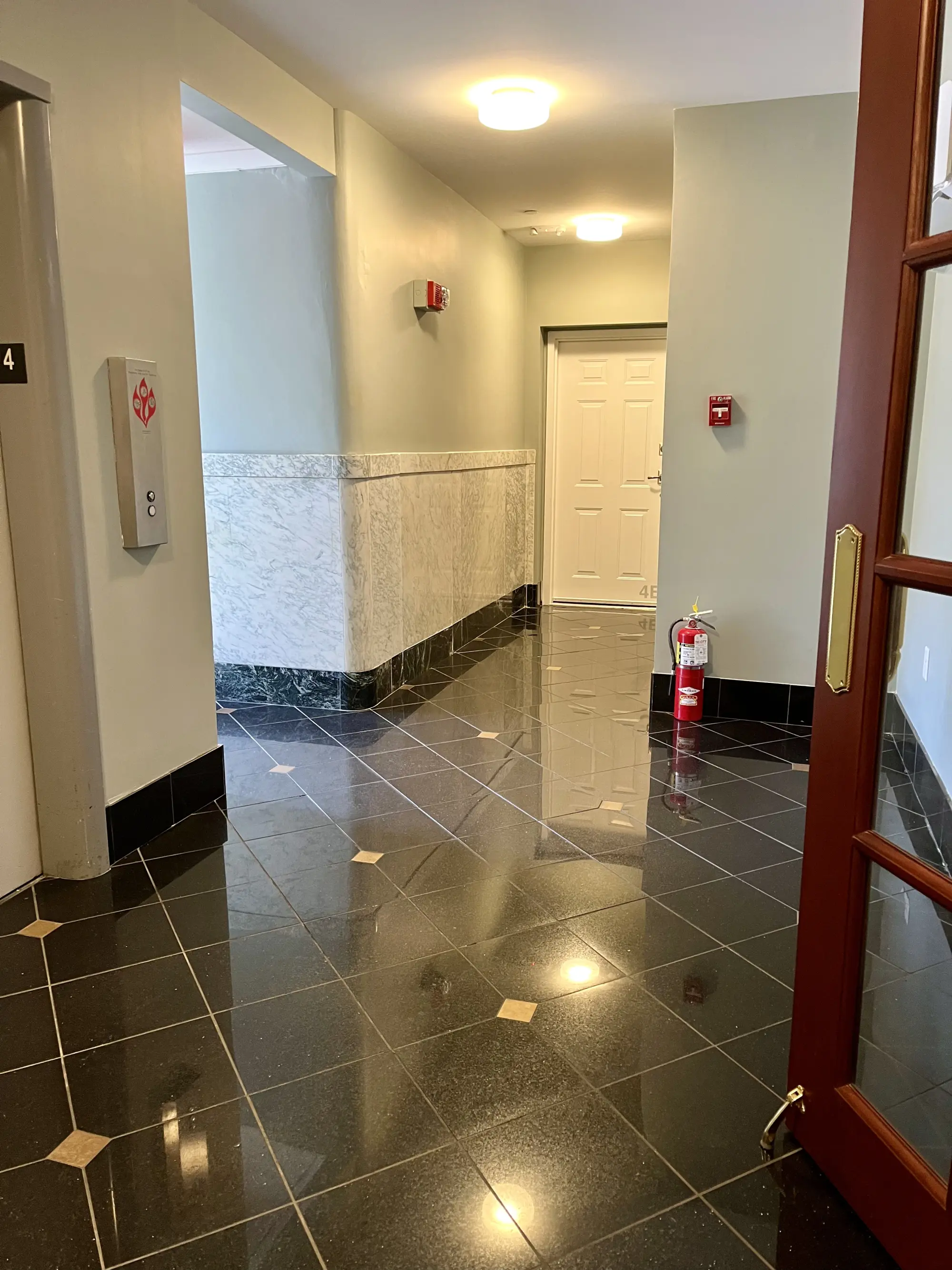 Polished black tile lobby with marble wainscoting in a historic Capital District building.