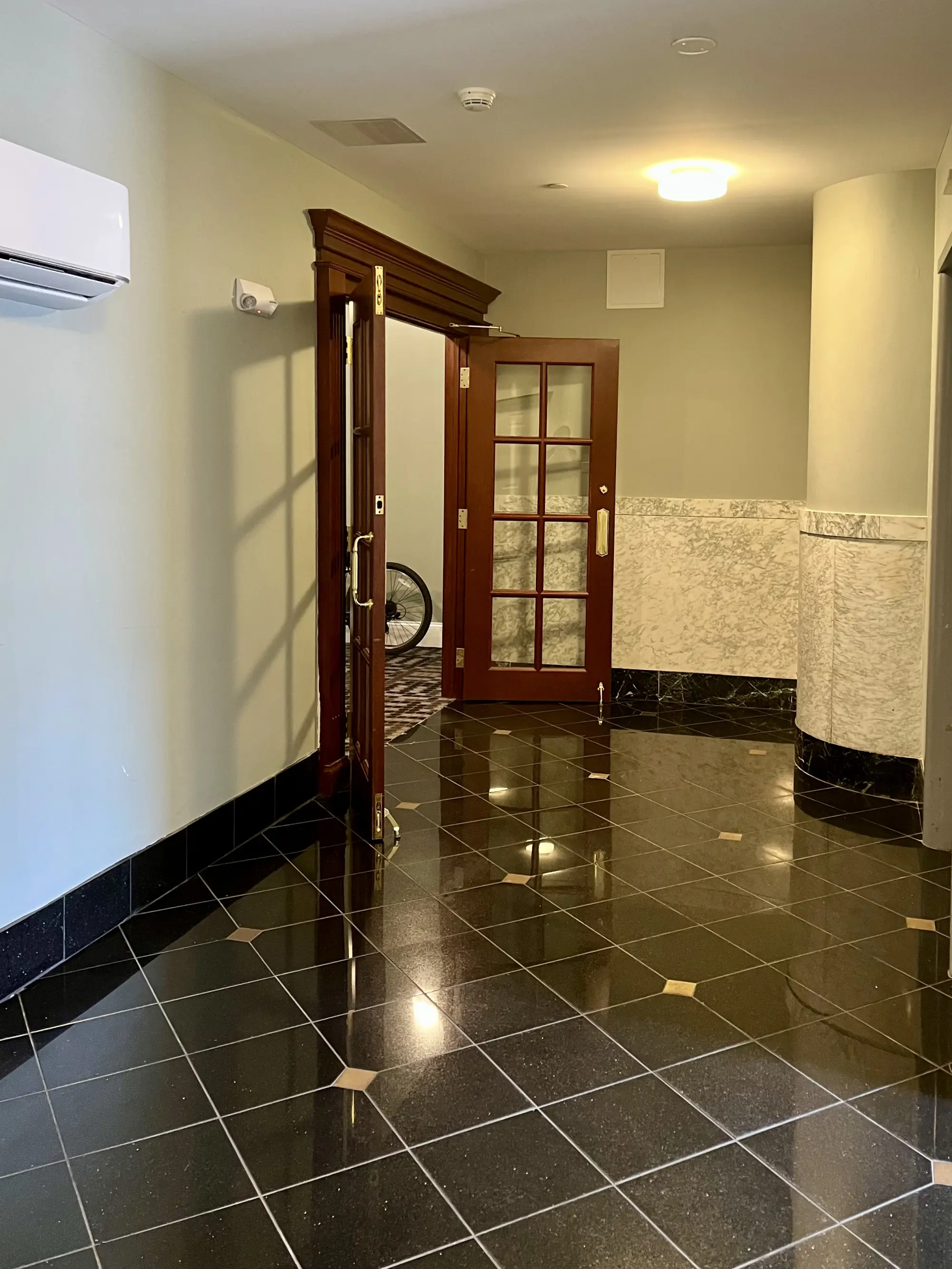 A polished black-tile entry vestibule with wood and glass doors in a historic Capital District building cleaned by Sandy Cares.