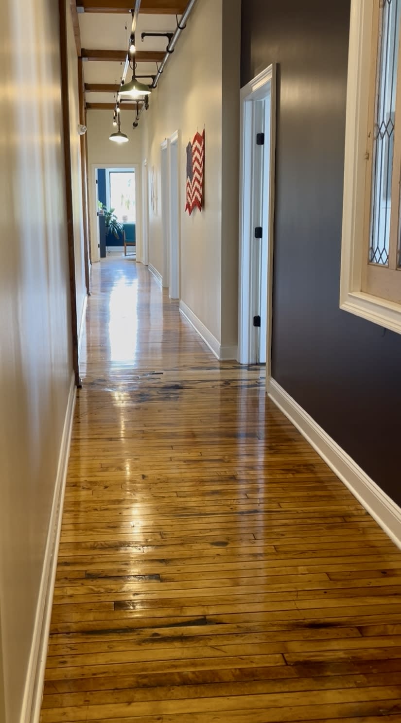 A long commercial hallway with laminate floors cleaned to a clean shine by Sandy Cares.