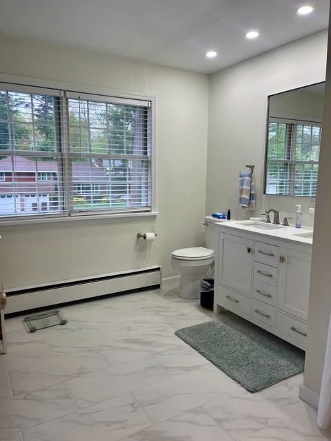 Spotless residential bathroom after Sandy Cares cleaning, featuring a white vanity, mirror, and gleaming tile floor.