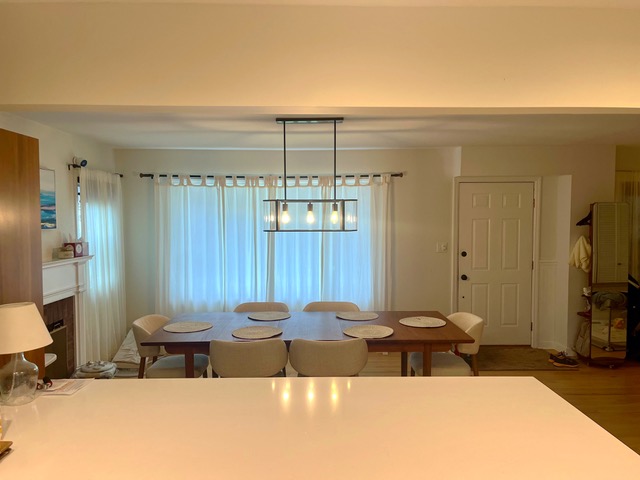 Tidy residential dining room cleaned by Sandy Cares, with a modern pendant light over a fully set table.